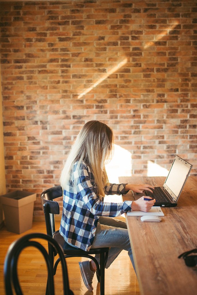 Persona escribiendo su plan de trabajo en una libreta, sobre un escritorio de madera
